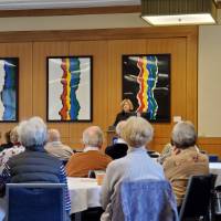 A woman speaks to people seated at round tables
